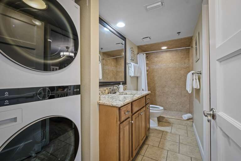 The guest bathroom offers a tile shower, granite countertops, and a convenient stacked washer and dryer, adding comfort and functionality to your stay