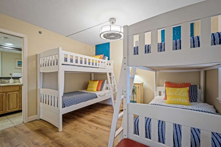 The guest bedroom features two twin bunk beds, a TV, and direct access to the guest bathroom, making it perfect for families