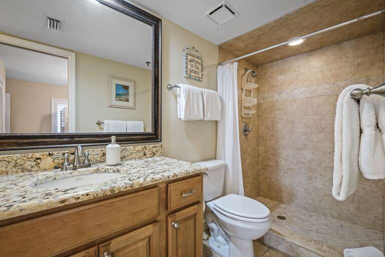 The updated guest bathroom features a tile shower and plush white spa towels