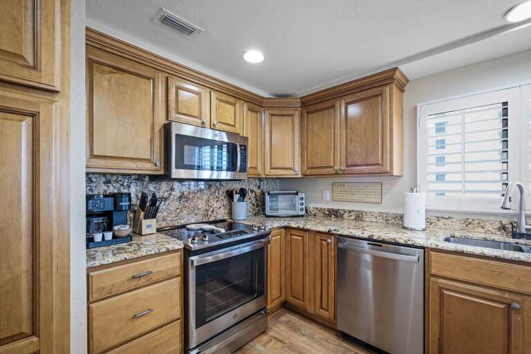 The updated kitchen features sleek granite countertops and brand-new stainless steel appliances, perfect for preparing meals during your beach getaway