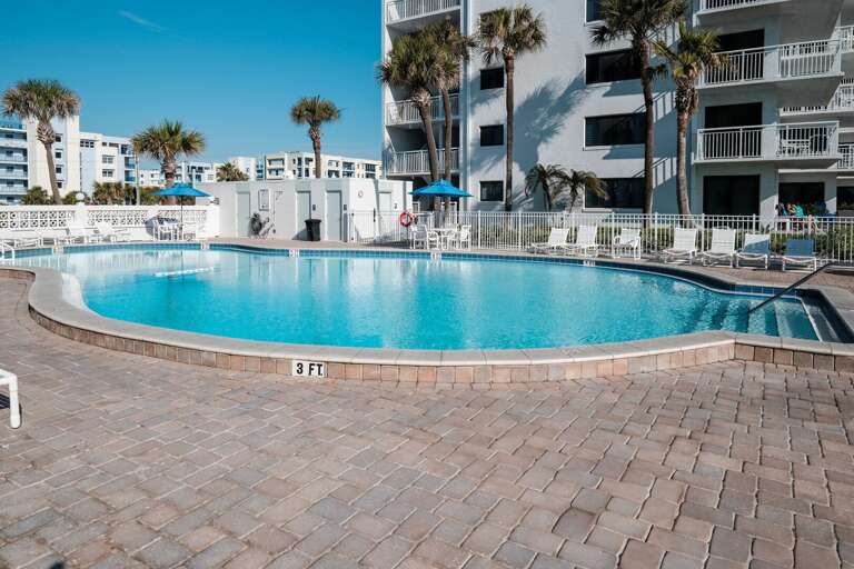 The beachfront pool deck at Shorehom by the Sea offers a heated pool, updated bathrooms, and plenty of chairs and tables for poolside lounging