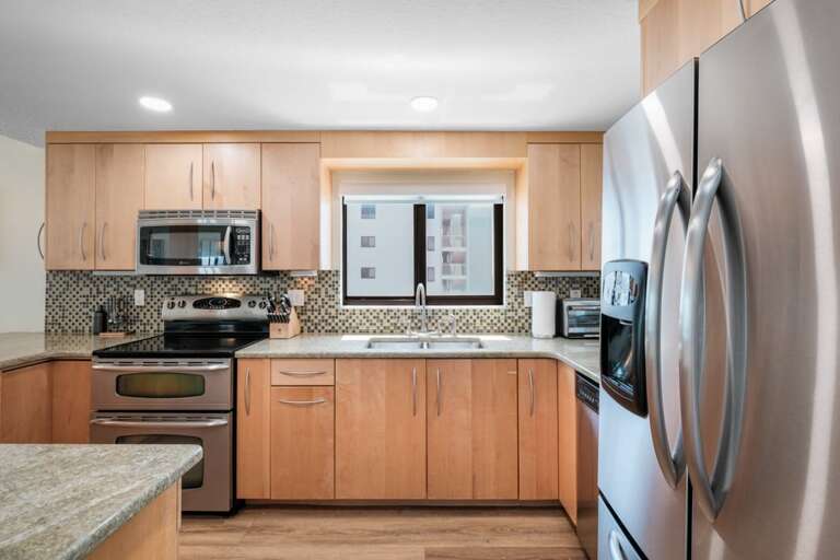 The kitchen features sleek stainless steel appliances, with the added bonus of a pool view from the kitchen sink