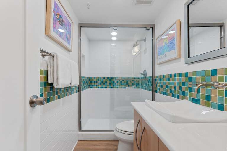 Refresh in the guest bathroom's glass and tile shower, perfect for a relaxing rinse after a day at the beach