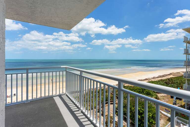 Unwind on the private corner balcony with panoramic views of New Smyrna's no-drive beach and the Shorehom by the Sea's pool