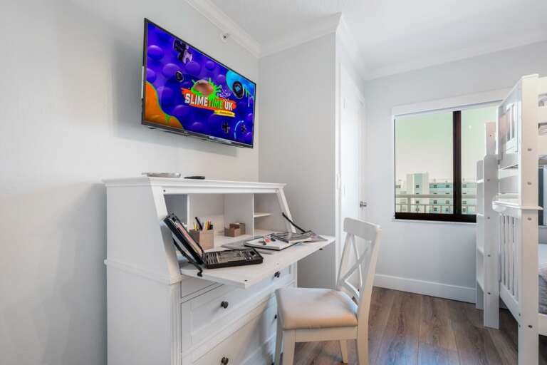 This versatile guest bedroom features a dedicated workspace with a desk and TV, making it an ideal spot for adults to work or for kids to enjoy activities