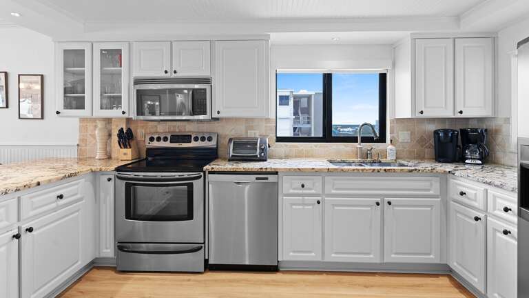 Cook in the fully equipped kitchen, featuring a window with a view of the Shorehom by the Sea pool Cook in the fully equipped kitchen, featuring a window with a view of the Shorehom by the Sea pool