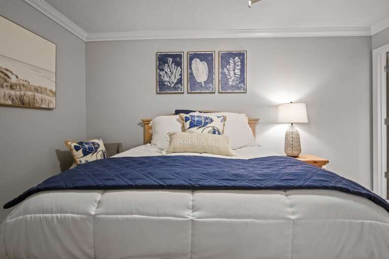 The master bedroom features a cozy queen bed adorned with soothing coastal blues