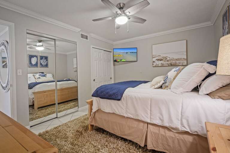 The master bedroom offers a cozy queen bed, a mounted TV for your entertainment, and closet storage