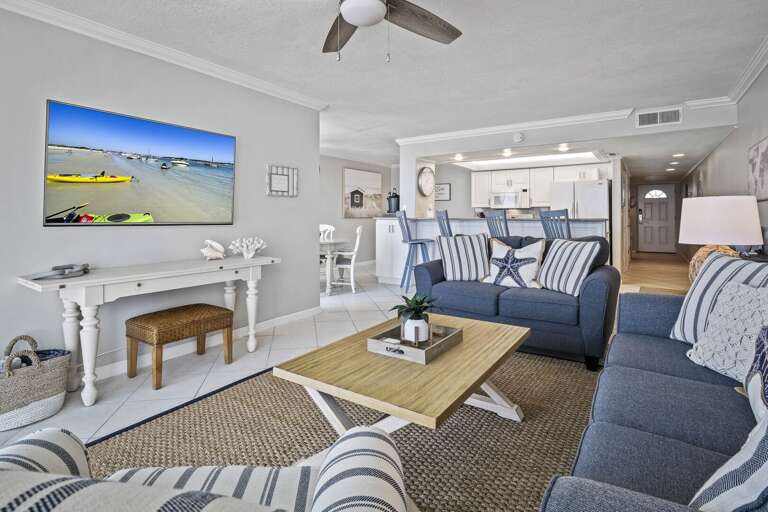 Relax in the comfortable oceanfront living room, featuring ample seating and a large TV. It's the ideal space to unwind after a day at the beach