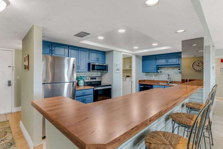 Cook with ease in the fully equipped kitchen featuring sleek stainless steel appliances and a vibrant pop of blue for a coastal touch Cook with ease in the fully equipped kitchen featuring sleek stainless steel appliances and a vibrant pop of blue for a coastal touch