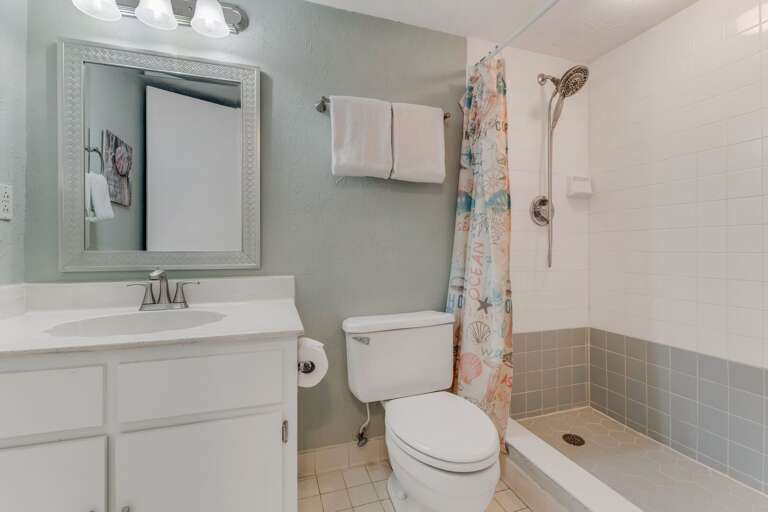 The guest bathroom features a stylish tile shower and plush white towels for a fresh, comfortable stay The guest bathroom features a stylish tile shower and plush white towels for a fresh, comfortable stay