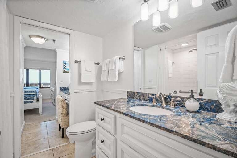 The northern guest bathroom features an updated tile shower and white, spa towels