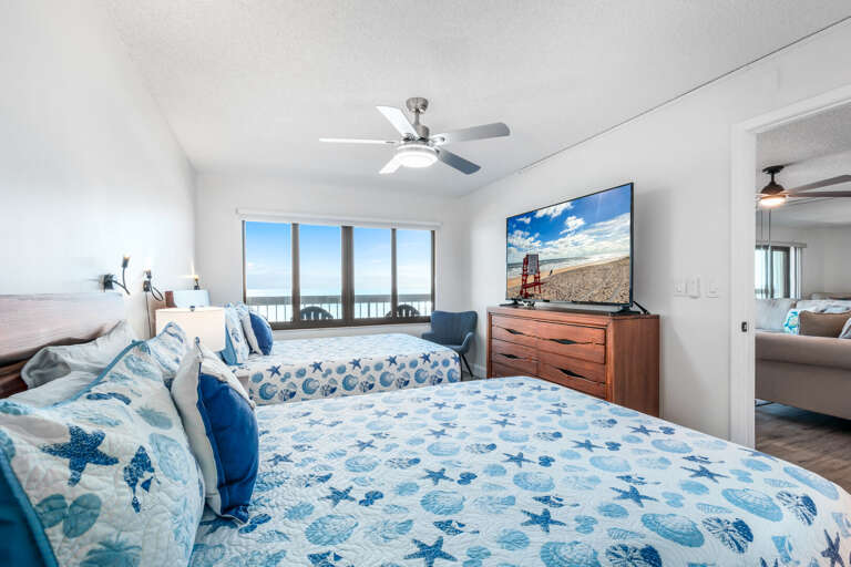 The oceanfront north guest bedroom features two comfy queen beds, a large TV, and incredible beach views—ideal for families or friends sharing the space The oceanfront north guest bedroom features two comfy queen beds, a large TV, and incredible beach views—ideal for families or friends sharing the space