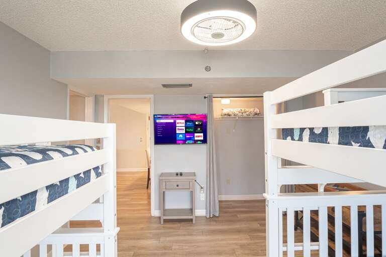 The guest bedroom has a TV, one full over full bunk bed, and one twin over twin bunk bed