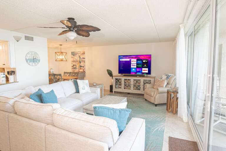 Unwind in the oceanfront living room featuring a large smart TV and a cozy sectional sofa, perfect for relaxing after a day at the beach Unwind in the oceanfront living room featuring a large smart TV and a cozy sectional sofa, perfect for relaxing after a day at the beach