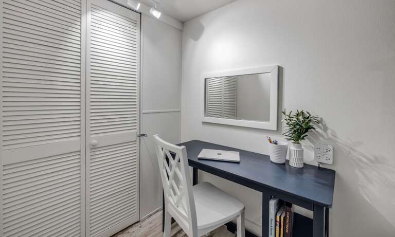 A dedicated workspace in the guest bedroom includes a desk, chair, and charging station—perfect for remote work with a beachside vibe