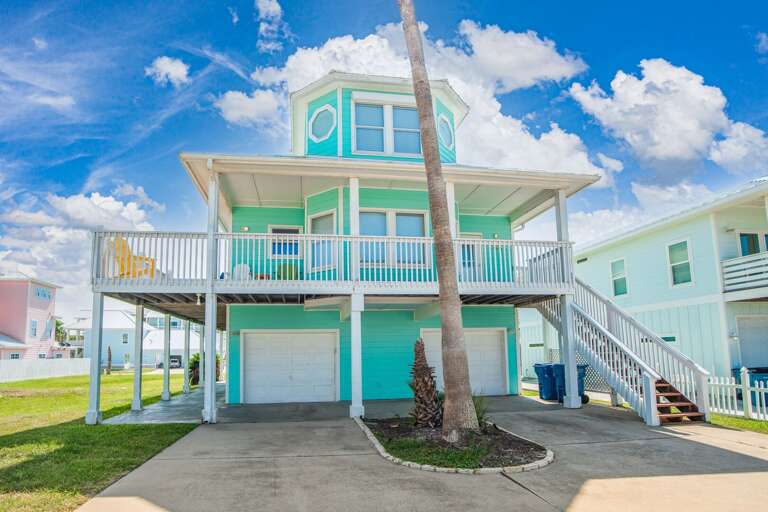 Two-story Beach House With Balconies And Garage Under A Blue Sky