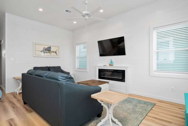Living Room With Blue Sofa, Coffee Table, And Mounted Television