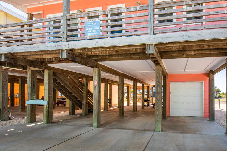 Wooden Walkway Under Structure With Stacked Balconies, Bright Beams, And Red Garage