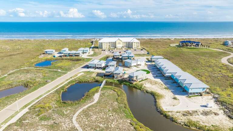 Aerial View Of Seaside Structures Surrounded By Serene Swamps