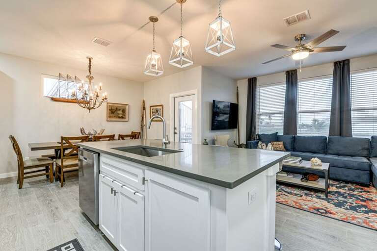 Spacious Kitchen Leading To Luminous Living Space, Sleek Surfaces With Suspended Lighting