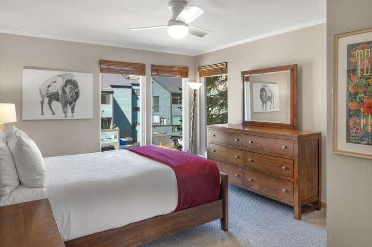 The primary bedroom offers a cozy queen bed, a spacious dresser, and plenty of natural light.