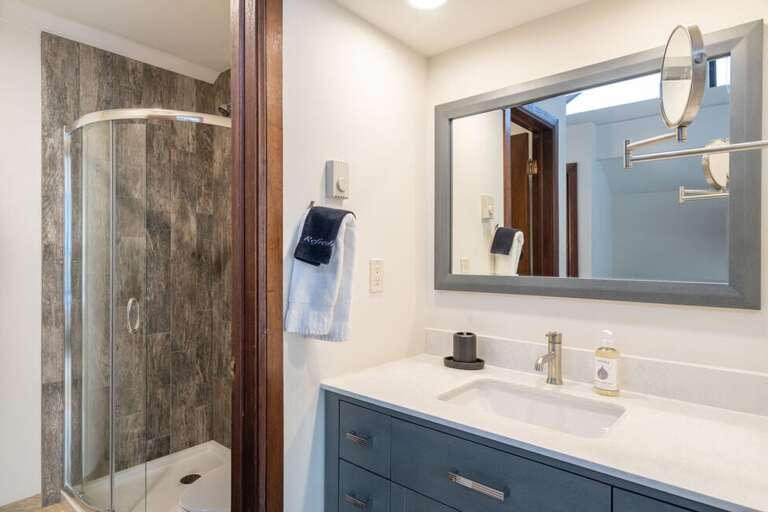 This guest room features an ensuite with walk-in shower and single sink vanity.