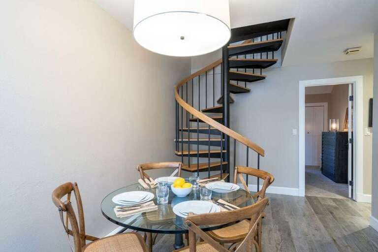 Dining for four to enjoy a home cooked meal or any delicious take out this town offers. The spiral stairs lead to the primary room. The second bedroom is in the background.