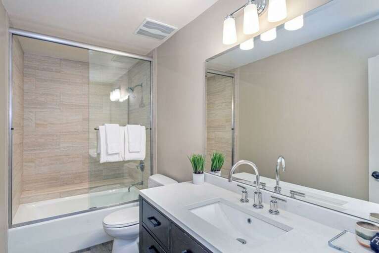 Modern bathroom next to second bedroom with tub/shower combo.