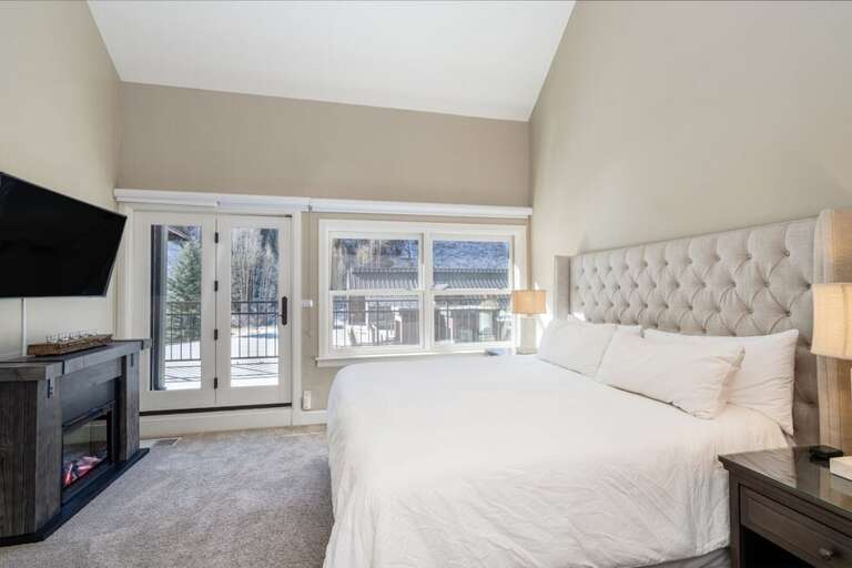 The primary suite offers a comfortable king bed, ensuite bathroom, cozy electric fireplace, and access to the shared outdoor deck