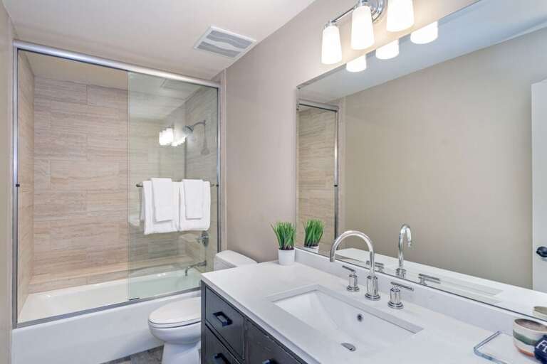 The shared bathroom, next to the guest room, includes a single vanity and a tub/shower combination.