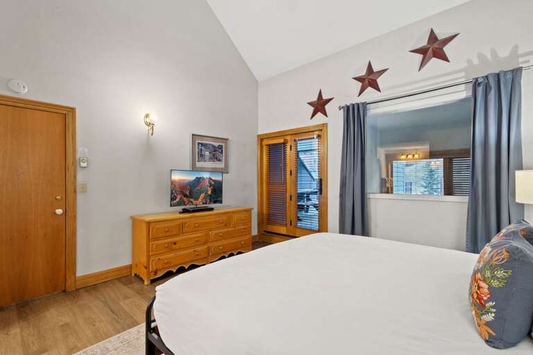 The Primary suite offers vaulted ceilings, a king bed, large closet, ensuite bathroom with step-in shower and tub, and direct access to the private deck.