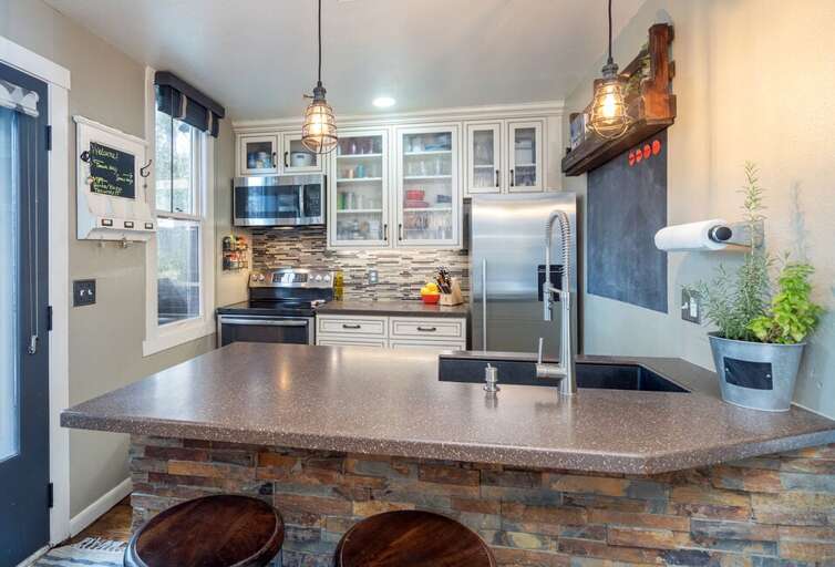 This adorable kitchen and breakfast bar feature a refrigerator, oven, microwave and small dishwasher.