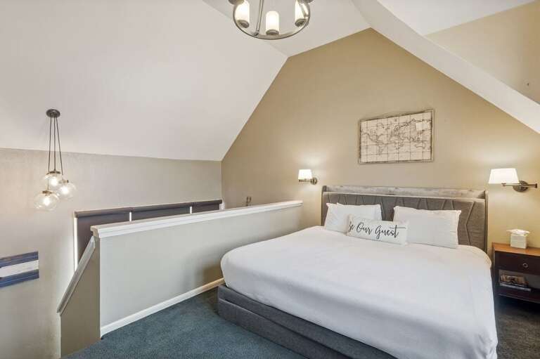 The lofted primary bedroom on the third level offers a cozy retreat with river views and an open connection to the living space below.