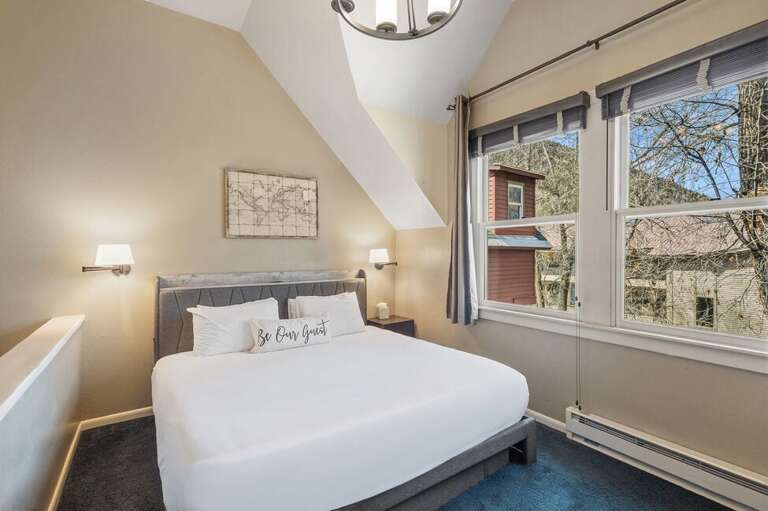 Perched as a loft on the third level, the primary bedroom is a warm, inviting retreat with sweeping river views and an airy connection to the living space below.