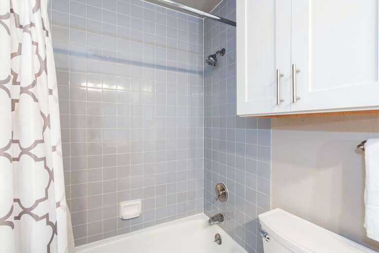 The bathroom has a combined shower/tub and washer + dryer + detergent