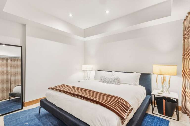 The lower-level guest room combines a king bed, sleek modern design, and private en suite for a tranquil getaway.