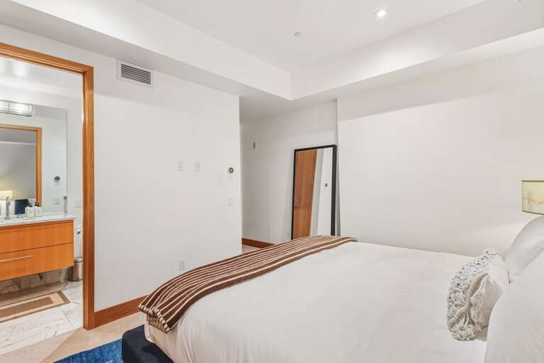 The lower-level guest room features a king bed, modern charm, and an en suite bathroom, offering a quiet retreat away from the main living areas.