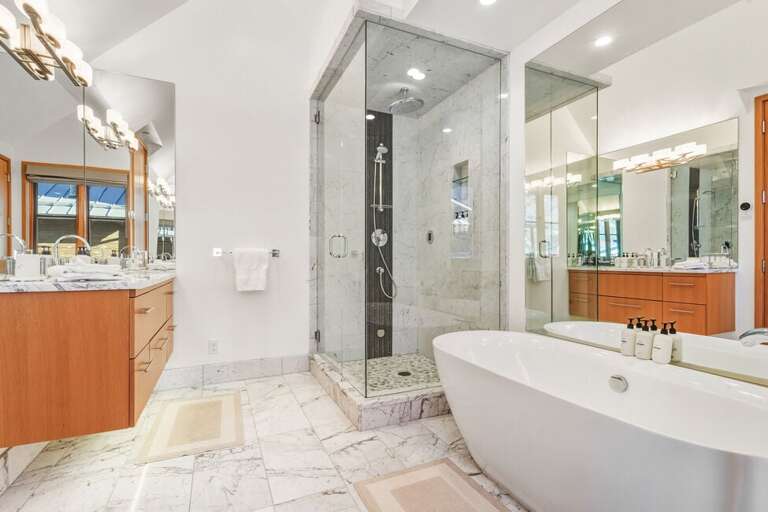 Luxury bathroom with soaking tub, dual vanity, water closet, step-in shower, and refined fixtures bathed in natural light.