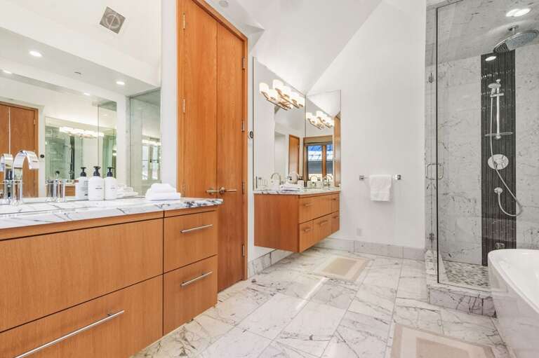 The luxury ensuite features a soaking tub, double vanity, water closet, step-in shower, abundant natural light, and exquisite fixtures with elegant, sophisticated style.
