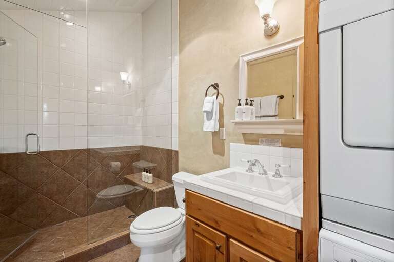 The shared guest bathroom features a step-in shower and a convenient stacked washer and dryer for easy, stress-free stays.