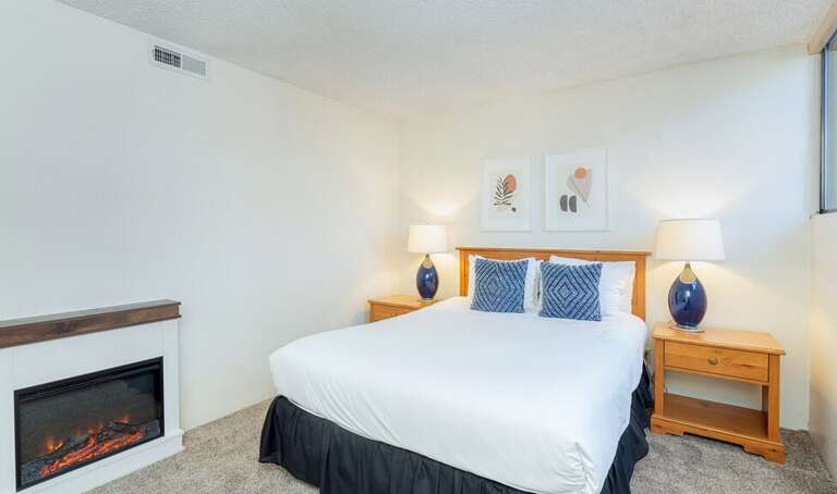 A different view of the queen bedroom on downstairs level complete with brand new electric fireplace to warms things up and keep it cozy.