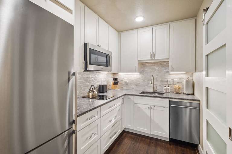 Bright, clean kitchen, induction cooktop, coffee maker and microwave.
