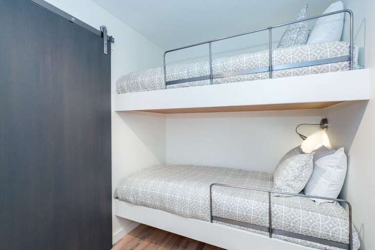 Each bunk has its own reading light, and a sliding door separates the primary bedroom from the bunk area.