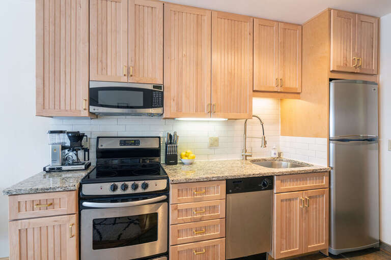 The kitchen is equipped with full sized, stainless appliances including a fridge, dishwasher & range.