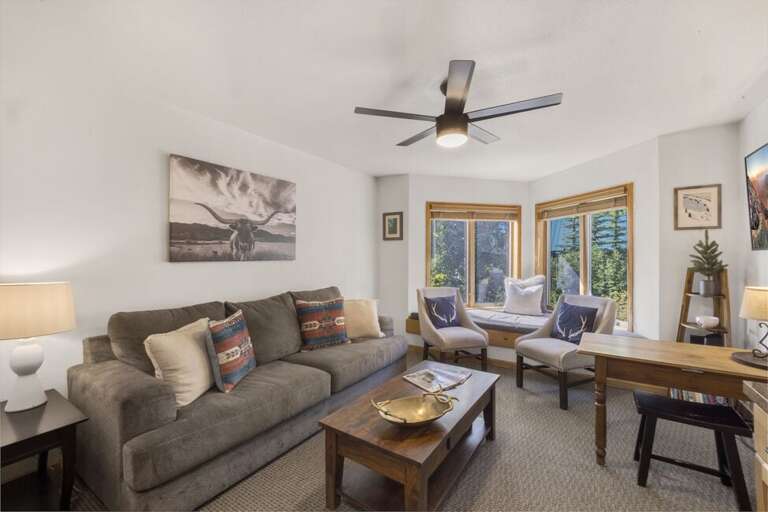 The living room has a large sofa facing a flat screen TV and a bay window with gorgeous views of the San Miguel River and Lift & ski runs.