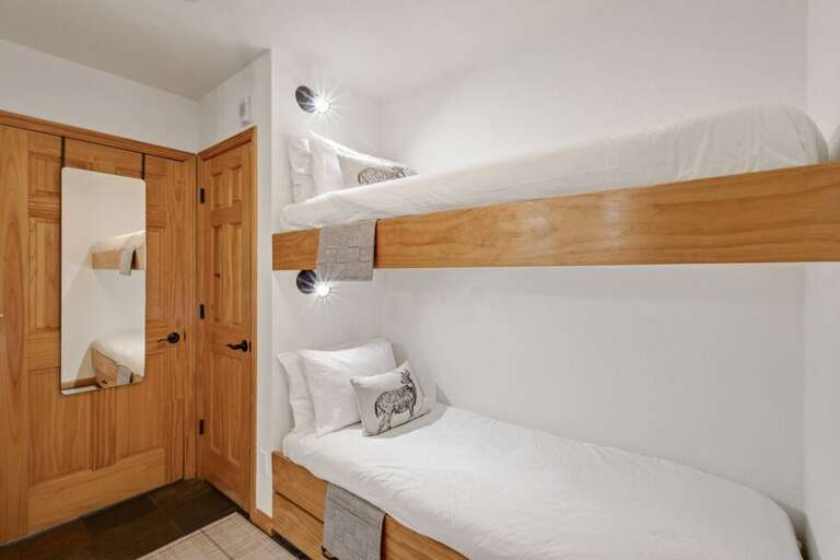 Twin bunk beds and a cozy vanity connect the bedroom and living area, creating a warm and inviting space.