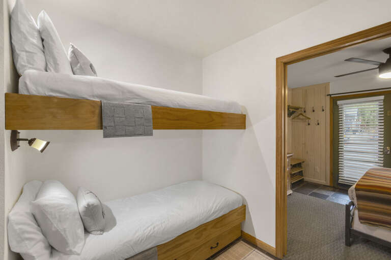 Twin bunk beds and a cozy vanity connect the bedroom and living area, creating a warm and inviting space.