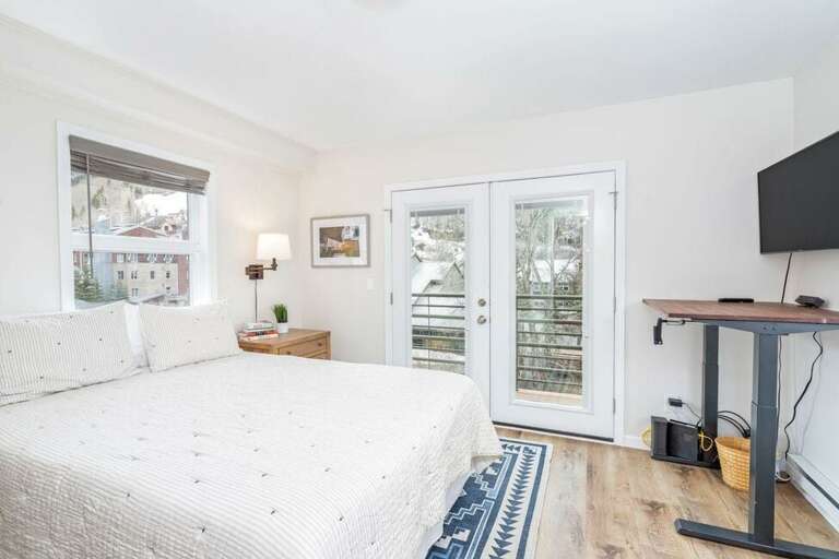 The queen bedroom has beautiful views in three directions, features a flat screen TV, and opens to a private balcony with ski area views.