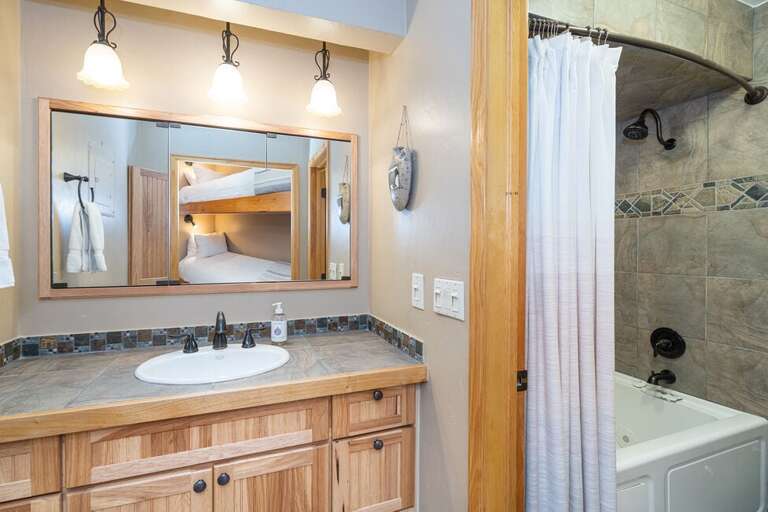 The bathroom is next to the bunks and has a combined shower and tub.